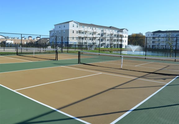 a group of tennis courts with buildings in the background