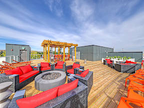 A wooden deck with red and black furniture and a fire pit.