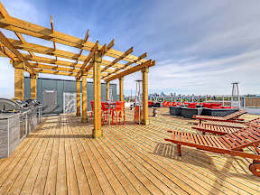 A wooden deck with red chairs and tables.