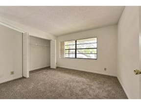 Carpeted bedroom with closet and window
