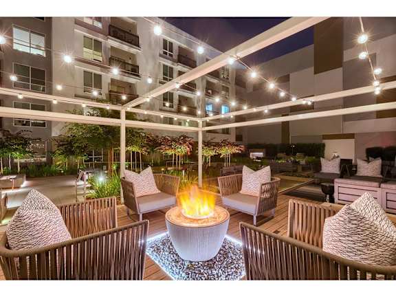 A patio with a fire pit and chairs.
