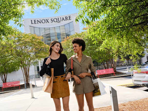 Three women are walking on a street with shopping bags.