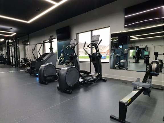 A gym with a variety of equipment including treadmills, stationary bikes, and weight machines.