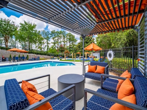 a swimming pool with chairs and tables under an umbrella