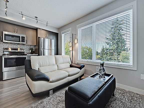 A modern kitchen with a white couch and a black ottoman.