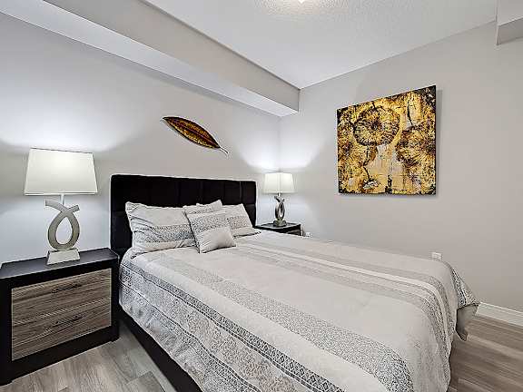 A bedroom with a bed, nightstand, and a painting on the wall.