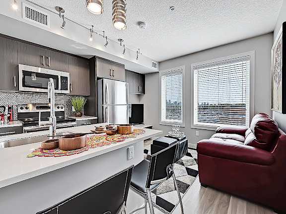 A modern kitchen with a red couch and black chairs.