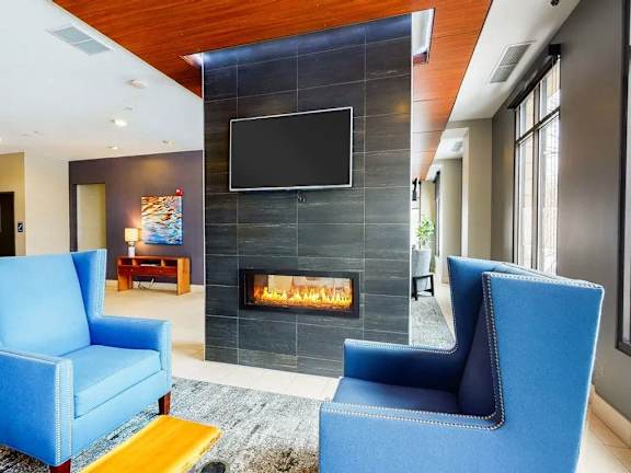 Two blue chairs are in front of a fireplace in a modern living room.