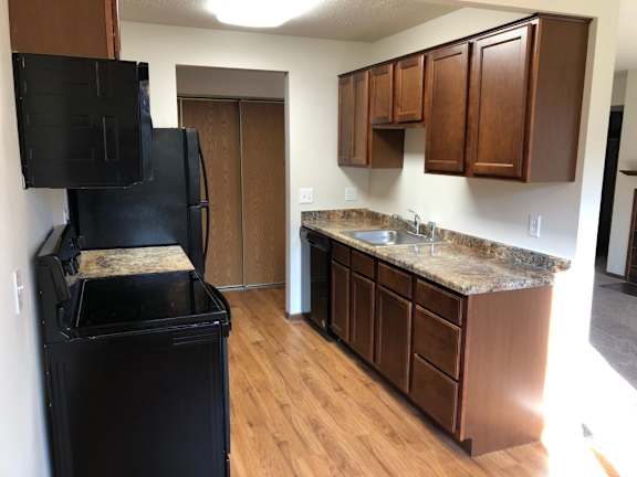 A black fridge in a kitchen with wooden cabinets.