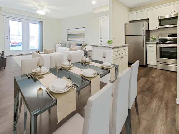 A modern kitchen with a glass dining table set for two.