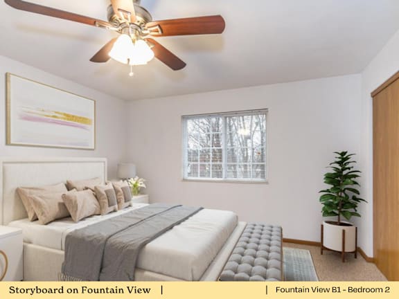 A bedroom with a bed, a ceiling fan, and a window.