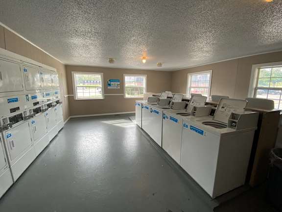 A laundromat with washers and dryers lined up.