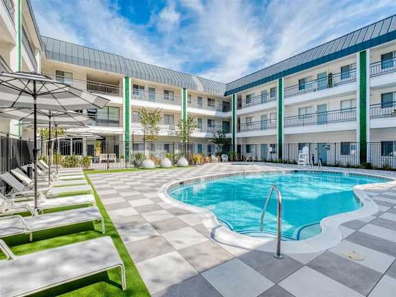 A large outdoor swimming pool surrounded by sun loungers and umbrellas.