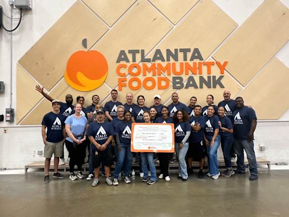 A group of people in blue shirts are standing in front of a sign that says "Atlanta Community Food Bank".