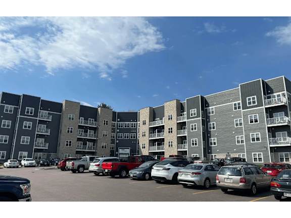 A parking lot with cars and apartment buildings in the background.