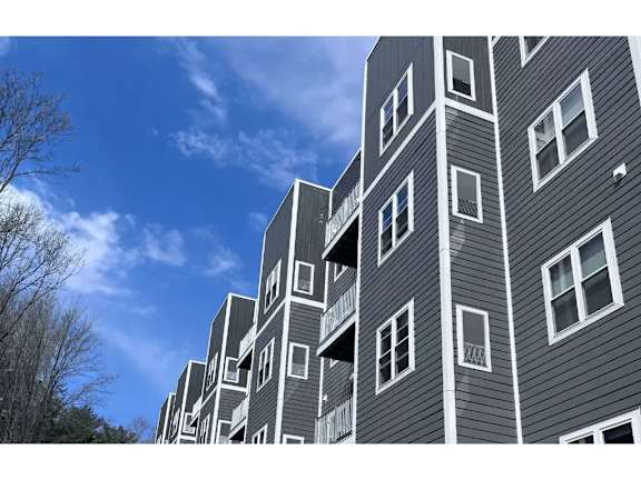A tall building with grey siding and white windows.