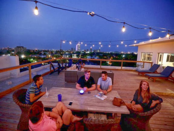 Four people sitting around a table on a rooftop. at The Mobile Lofts, Alabama, 36604