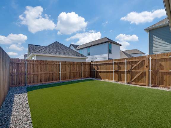 A backyard with a green lawn and a wooden fence.
