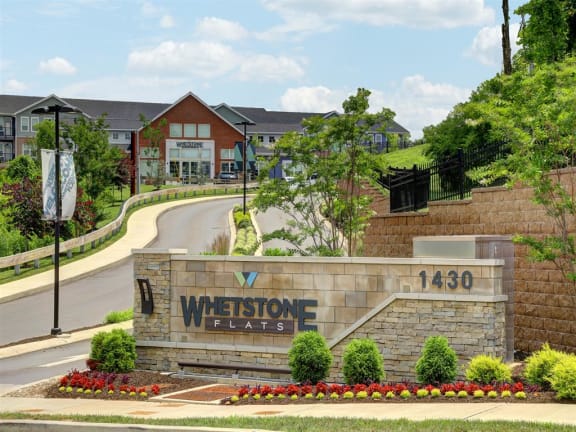 the sign for weststone flats in front of a road and houses