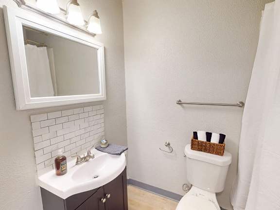 A white toilet with a black and white striped towel on top of it.