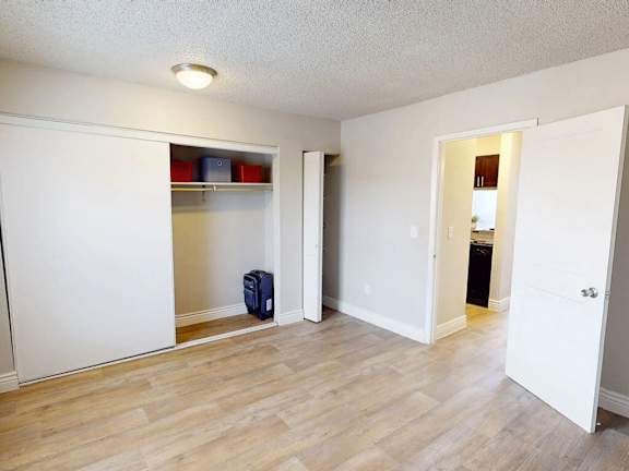 A room with a white door and a blue suitcase on the floor.