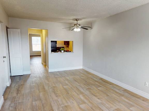 A room with a ceiling fan and wooden flooring.
