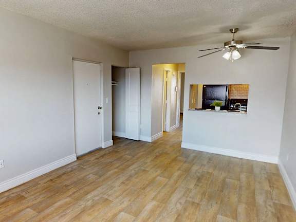 A room with a ceiling fan and wooden flooring.