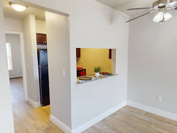 A kitchen with a black refrigerator and a small counter with a plant on it.