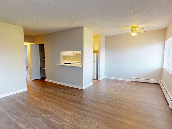 A room with a ceiling fan and a window with blinds.