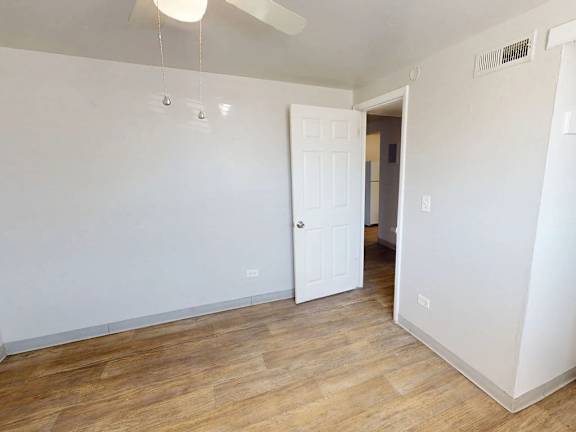 A room with a white door and a ceiling fan.