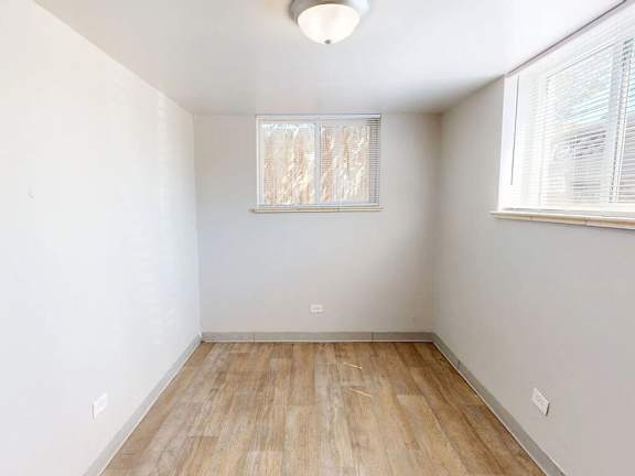 A room with wooden flooring and a window with blinds.