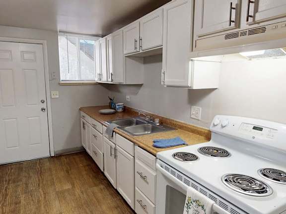 A white stove is in a kitchen with white cabinets.
