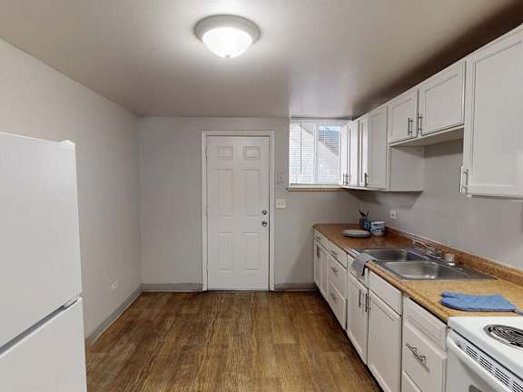 A kitchen with white appliances and wooden floors.
