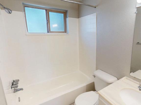 A white bathroom with a toilet, sink, and bathtub.