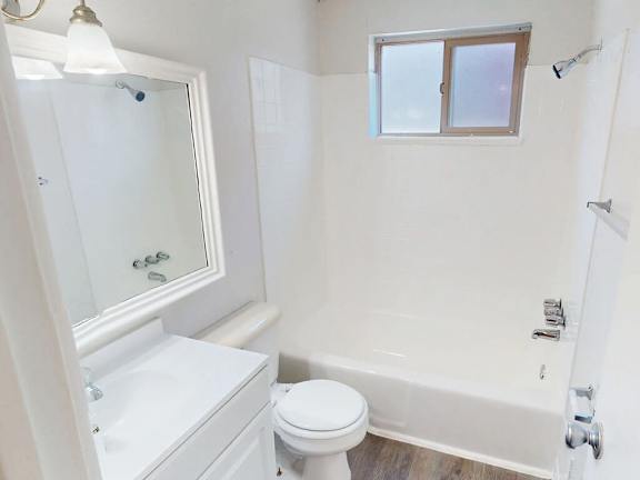 A white toilet sits next to a white bathtub in a bathroom.
