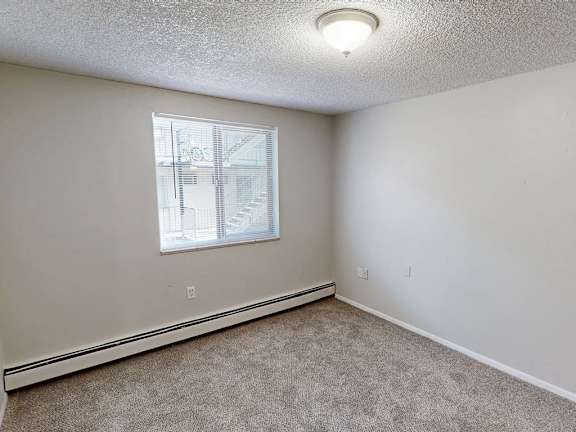 A room with a window and carpeted floor.