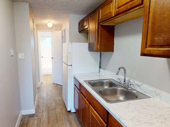 A kitchen with a white fridge and wooden cabinets.