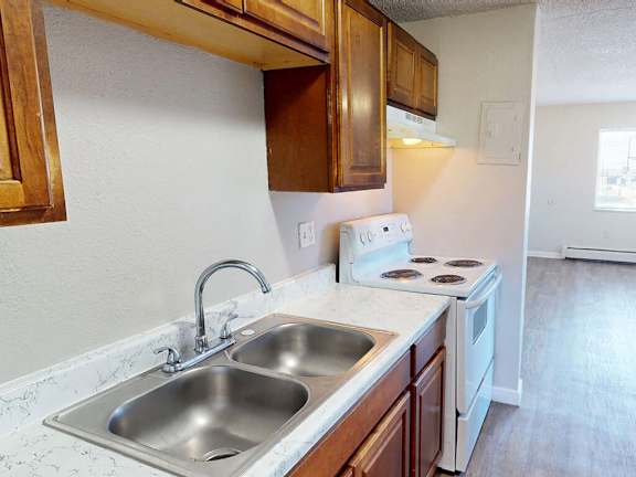 A kitchen with a stove, sink, and cabinets.