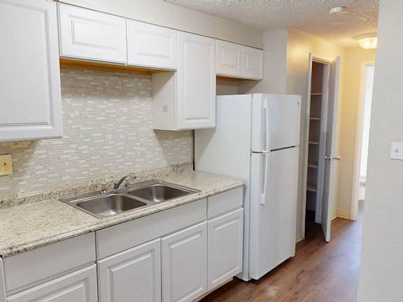 A kitchen with white cabinets and a white refrigerator.