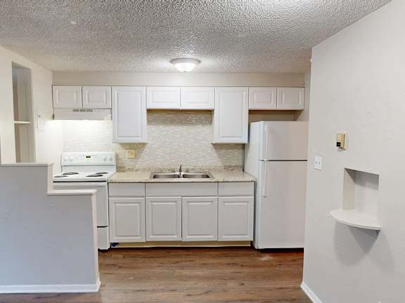 A kitchen with white cabinets and a white refrigerator.