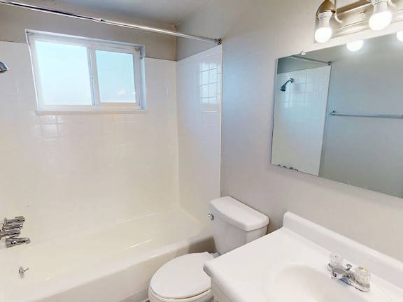 A white bathroom with a toilet, sink, and bathtub.