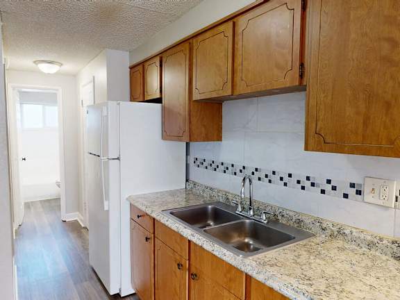 A kitchen with a white refrigerator and wooden cabinets.