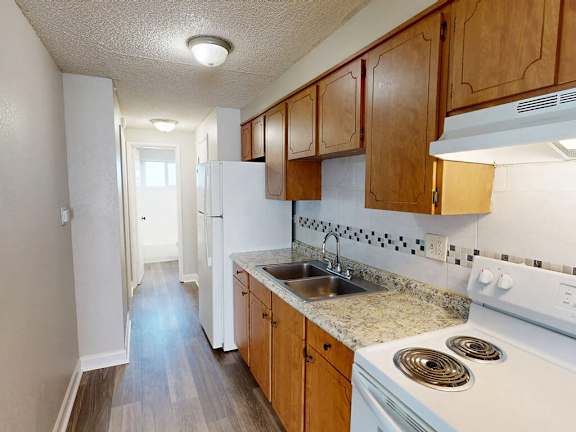 A kitchen with white appliances and wooden cabinets.