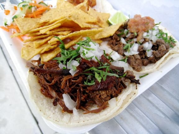 a taco with meat and onions on a plate with chips