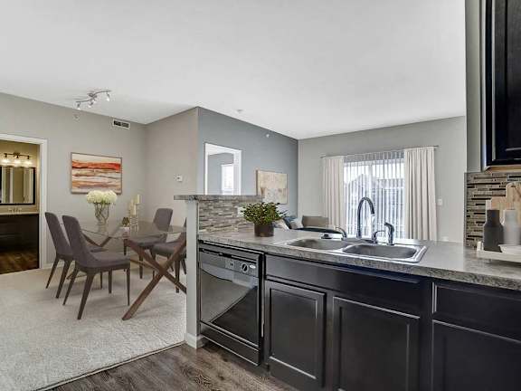 a living room with a couch a chair a table and a kitchen in the background