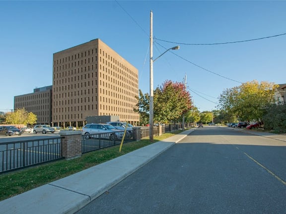 A brown building with a black awning sits between a modern glass building and a brick building.