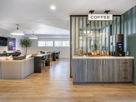 a kitchen with a counter and a coffee machine in a room with a living room