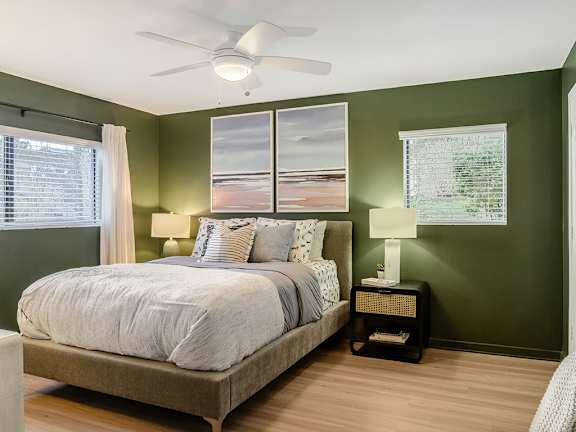 a bedroom with green walls and a ceiling fan