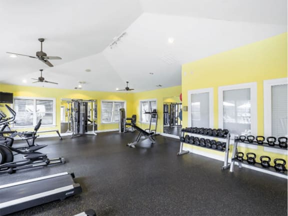 a gym with weights and a ceiling fan