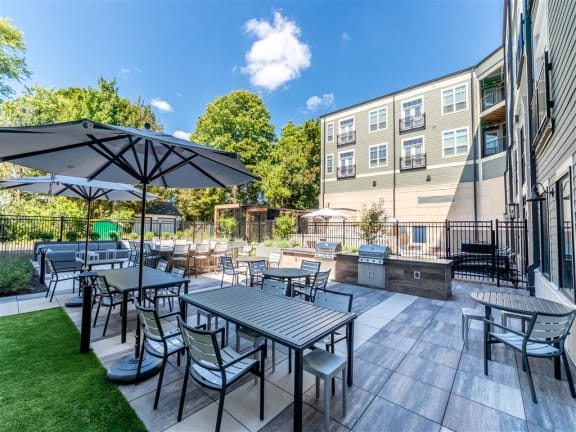 A patio with a table and chairs is surrounded by a grassy area and a building at The Foundry Apartments , South Bend, IN, 46617